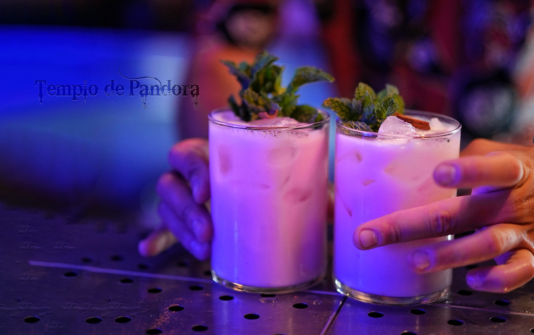 Dos cócteles de color blanco con hojas de menta sobre la barra de la coctelería
